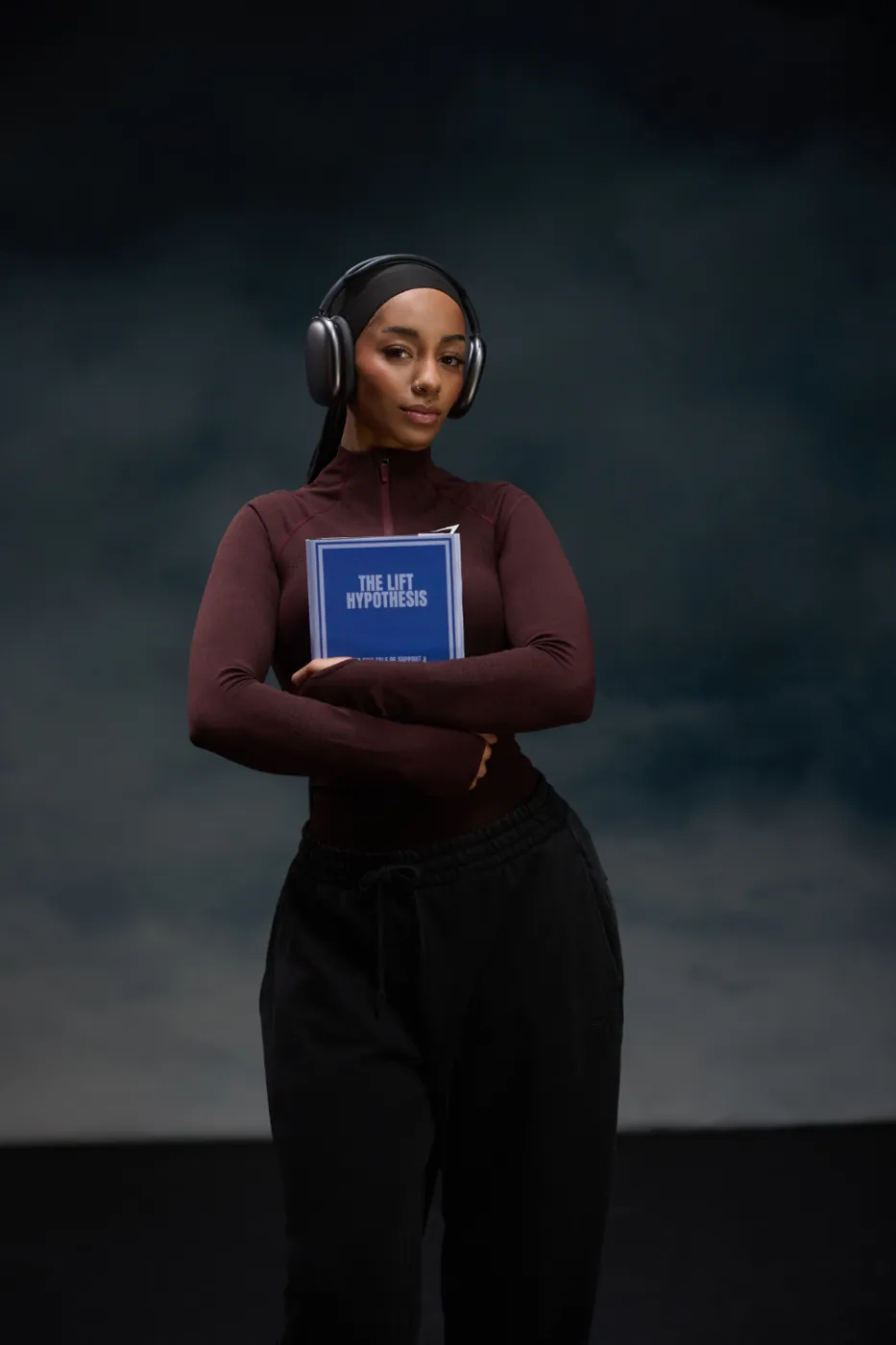 Aliya holding a book, headphones on, before training
